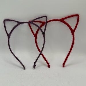 Two cat ear headbands: one red, one purple